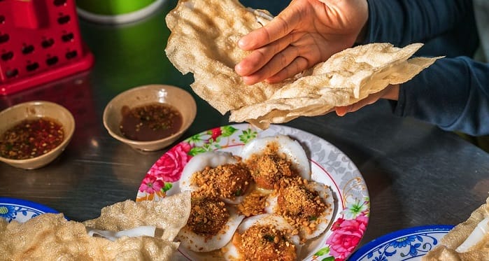 Nếu vẫn chưa biết ăn gì khi đến Hội An, bạn nhất định phải thử qua quán bánh đập nổi tiếng tại Cẩm Nam. Món bánh đập ở đây không chỉ là đặc sản mà còn là hương vị níu chân bao thế hệ thực khách. Từ xa, bạn đã có thể cảm nhận được mùi thơm nồng nàn của gạo mới, bánh tráng nướng giòn rụm quyện cùng bát nước chấm hành đặc trưng. Hấp dẫn nhất là phần hến xào được đánh bắt trực tiếp từ cồn Hến, ngọt thịt, đậm đà, ăn kèm bánh đập thì cứ gọi là "vừa bùi vừa mê". Một lần thưởng thức là nhớ mãi không quên!